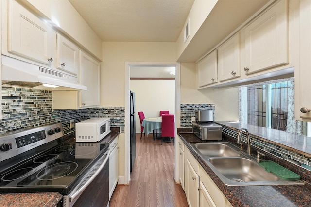 kitchen with white microwave, under cabinet range hood, a sink, electric stove, and dark countertops