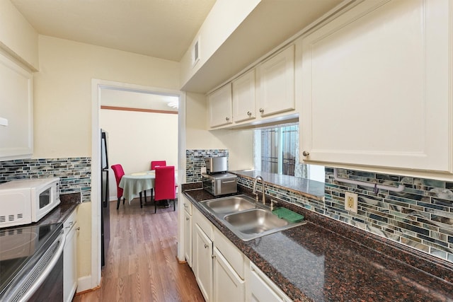 kitchen with white microwave, a sink, light wood-style floors, electric stove, and backsplash