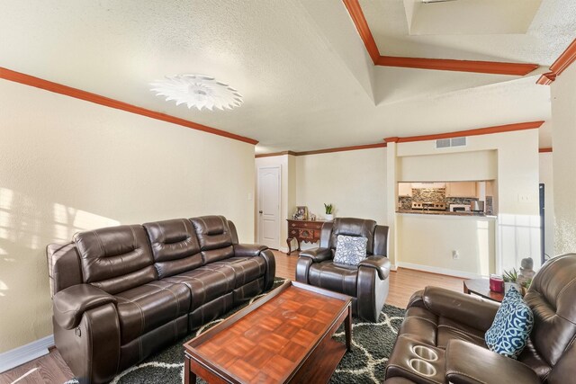 living room with ornamental molding, visible vents, a textured ceiling, and wood finished floors