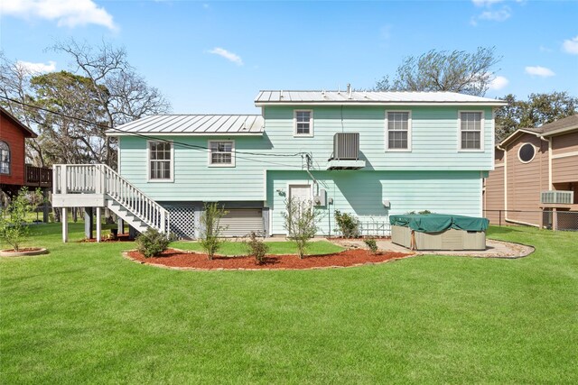 back of property featuring fence, stairway, metal roof, and a lawn