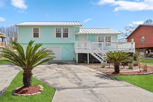 view of front of property with concrete driveway, stairway, an attached garage, a standing seam roof, and metal roof