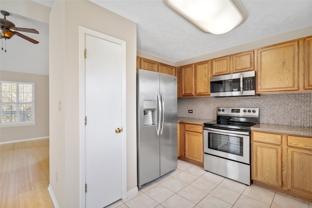 kitchen with light tile patterned floors, baseboards, decorative backsplash, a ceiling fan, and stainless steel appliances