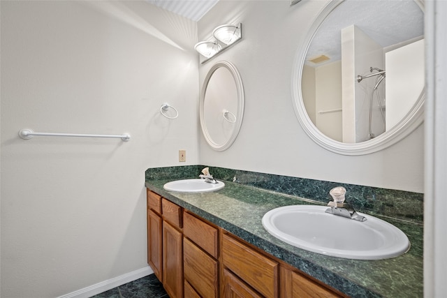 full bath featuring double vanity, baseboards, and a sink