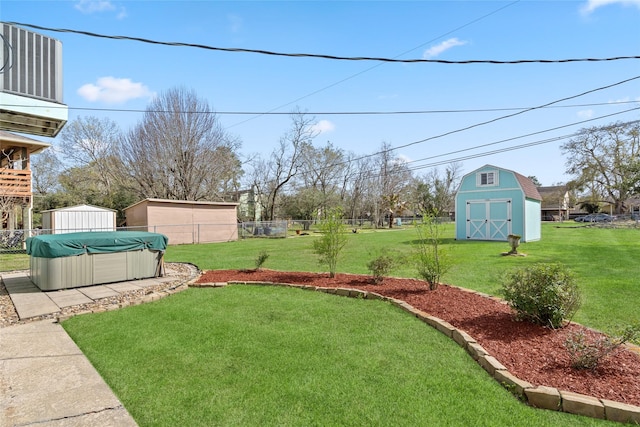 view of yard with a swimming pool, fence, a storage unit, and an outbuilding