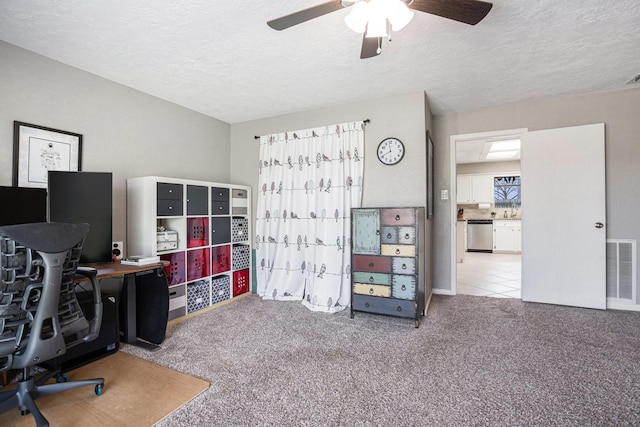 office featuring visible vents, carpet flooring, a textured ceiling, and a ceiling fan