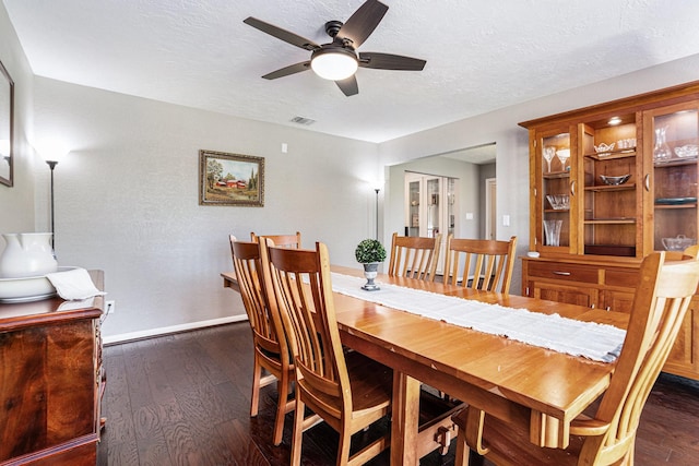 dining space featuring visible vents, dark wood-type flooring, ceiling fan, baseboards, and a textured ceiling