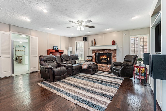 living room featuring a fireplace, wood finished floors, a wealth of natural light, and a ceiling fan