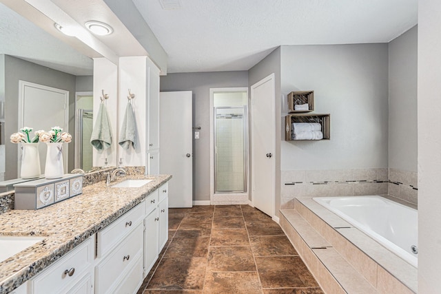 bathroom featuring vanity, baseboards, a shower stall, a textured ceiling, and a bath