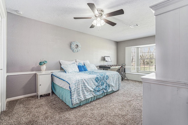 bedroom with visible vents, a textured ceiling, carpet, and a textured wall