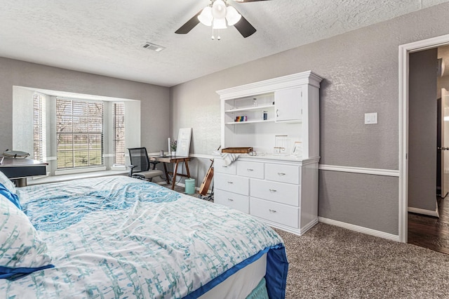 bedroom with a textured wall, baseboards, carpet floors, and a textured ceiling