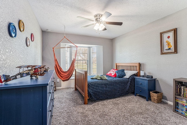 carpeted bedroom featuring a ceiling fan, a textured wall, and a textured ceiling