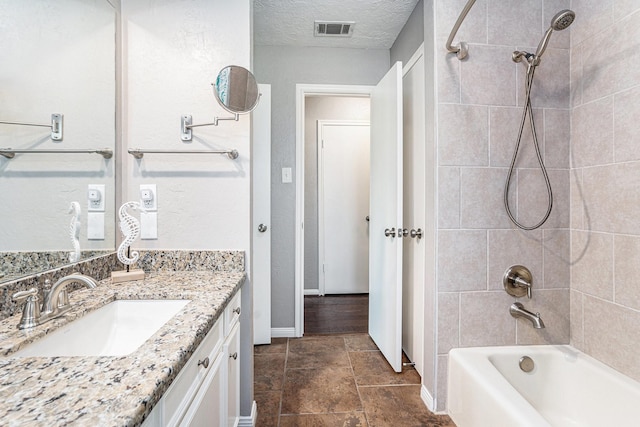 full bath with visible vents, a textured ceiling, washtub / shower combination, baseboards, and vanity