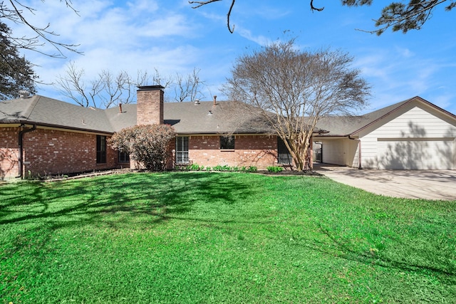 view of front of house featuring a front yard, concrete driveway, brick siding, and a chimney