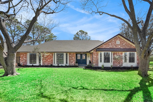 ranch-style home featuring a front yard, brick siding, and a shingled roof