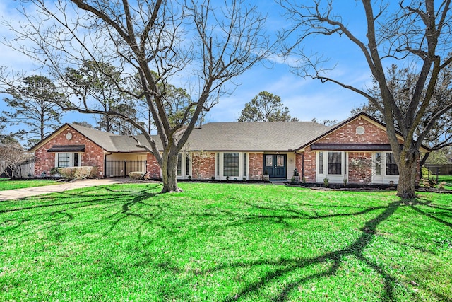 ranch-style home featuring a garage, brick siding, concrete driveway, and a front lawn