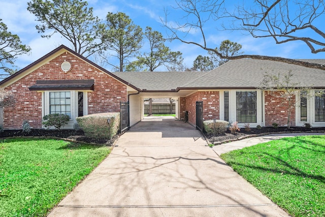 single story home featuring brick siding, a front yard, a carport, and driveway