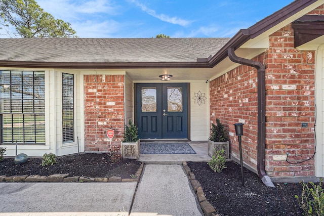 doorway to property featuring brick siding and a shingled roof