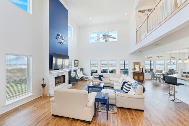 living area with a fireplace, visible vents, ornamental molding, ceiling fan, and wood finished floors