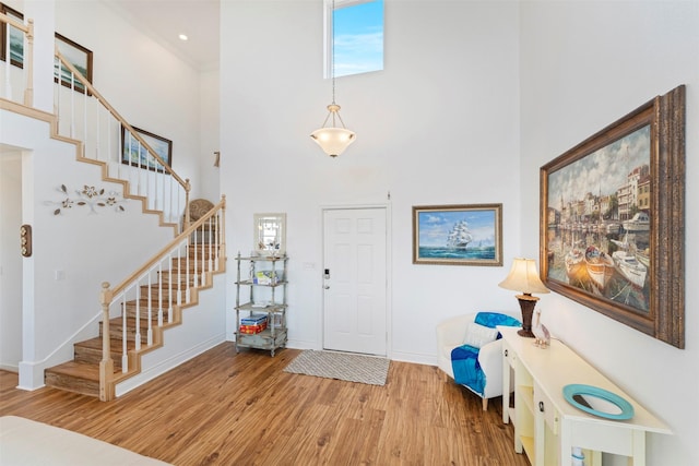 entryway featuring a high ceiling, stairs, baseboards, and wood finished floors