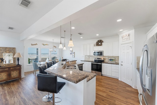 kitchen with visible vents, decorative backsplash, dark wood-type flooring, stainless steel appliances, and a sink