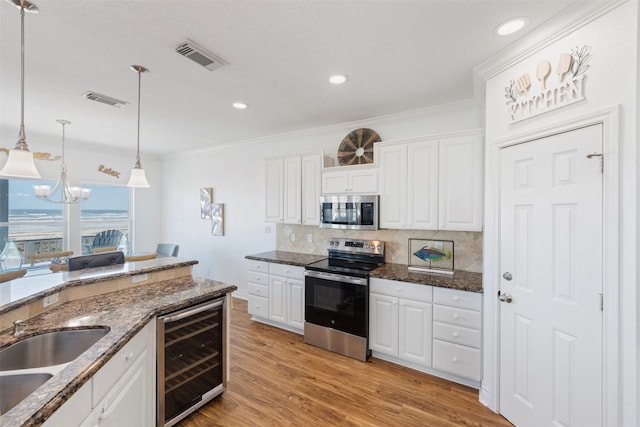 kitchen with visible vents, backsplash, appliances with stainless steel finishes, light wood-type flooring, and beverage cooler