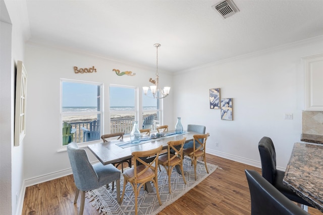 dining room featuring baseboards, crown molding, visible vents, and wood finished floors