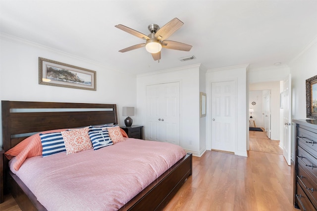 bedroom featuring light wood finished floors, visible vents, a ceiling fan, crown molding, and a closet