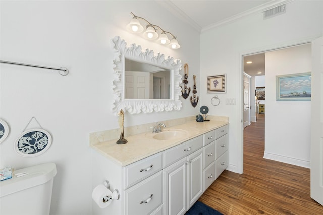 bathroom featuring visible vents, toilet, ornamental molding, vanity, and wood finished floors