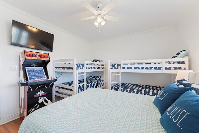 bedroom featuring ceiling fan, crown molding, baseboards, and wood finished floors