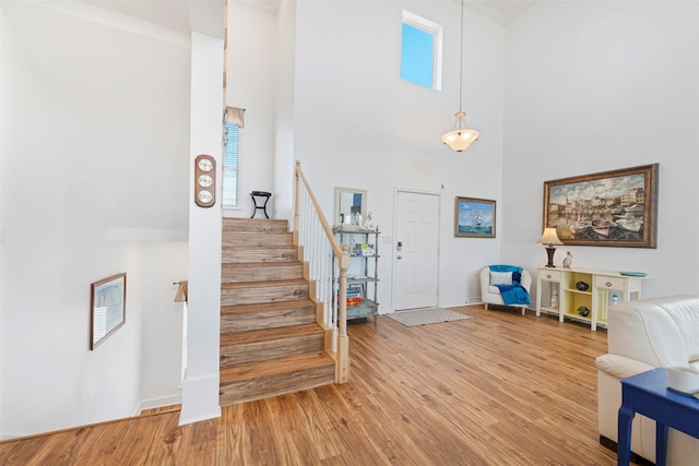 foyer entrance with wood finished floors, a towering ceiling, baseboards, and stairs