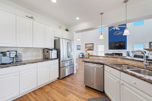 kitchen with appliances with stainless steel finishes, crown molding, a sink, and white cabinetry