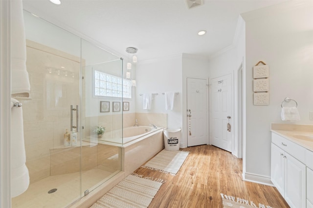 full bath with wood finished floors, vanity, a shower stall, a bath, and crown molding