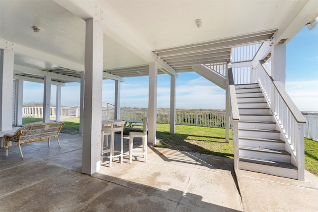 view of patio / terrace featuring stairs, fence, and outdoor dining area