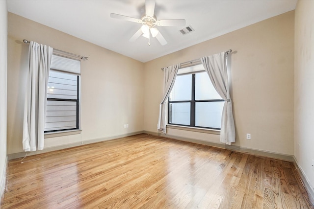 spare room with baseboards, visible vents, ceiling fan, and wood finished floors