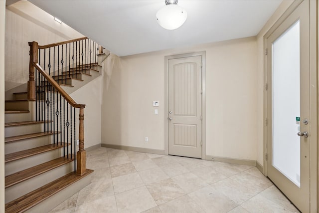 entrance foyer with light tile patterned flooring, stairway, and baseboards