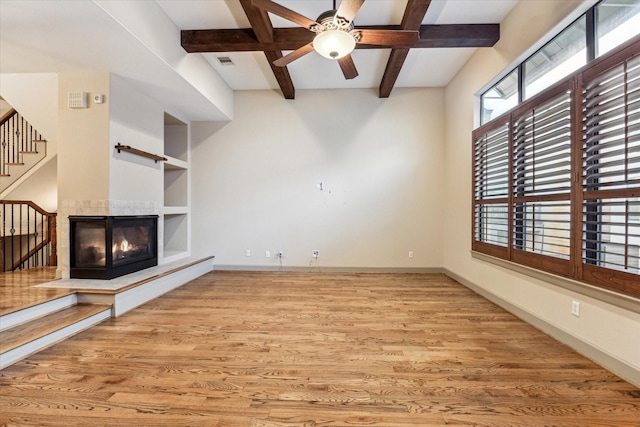 unfurnished living room featuring baseboards, built in features, wood finished floors, and a multi sided fireplace