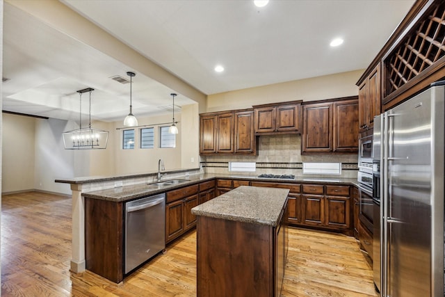 kitchen with stainless steel appliances, a peninsula, a kitchen island, visible vents, and light wood-type flooring