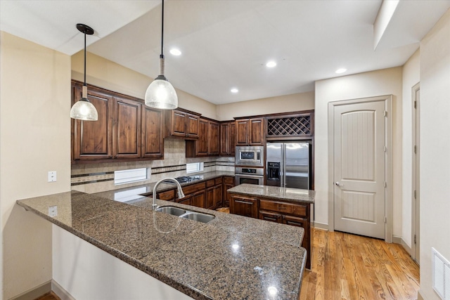 kitchen with dark stone counters, stainless steel appliances, tasteful backsplash, and a sink