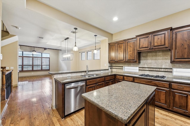 kitchen featuring gas stovetop, visible vents, a sink, light stone countertops, and dishwasher