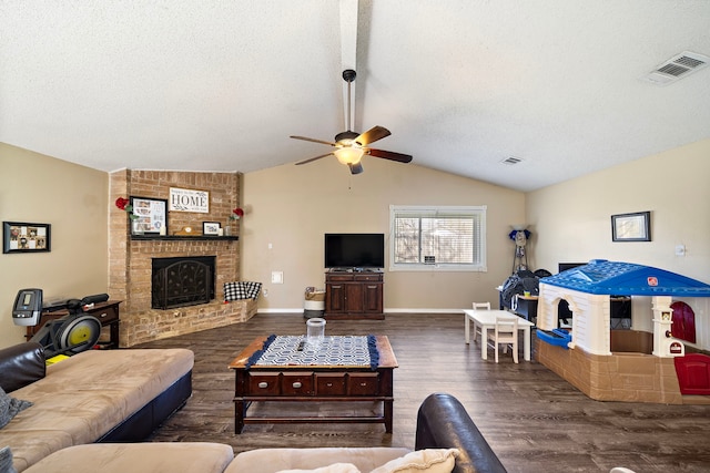 living area featuring visible vents, wood finished floors, a fireplace, and vaulted ceiling