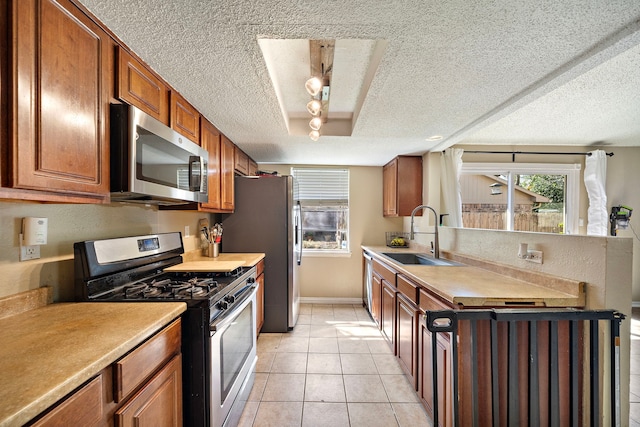 kitchen with light tile patterned floors, appliances with stainless steel finishes, a textured ceiling, and a sink