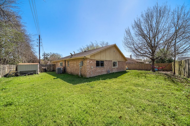 rear view of property featuring a yard, brick siding, and a fenced backyard