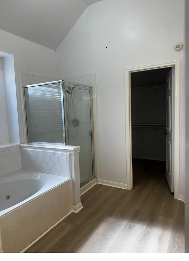 full bathroom with vaulted ceiling, a stall shower, wood finished floors, and a bath