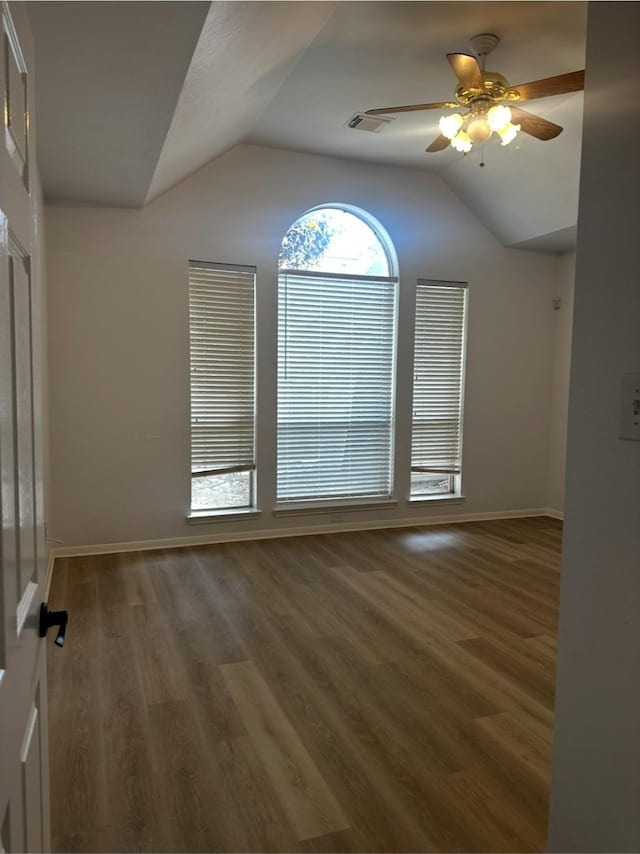 empty room with baseboards, visible vents, a ceiling fan, wood finished floors, and vaulted ceiling