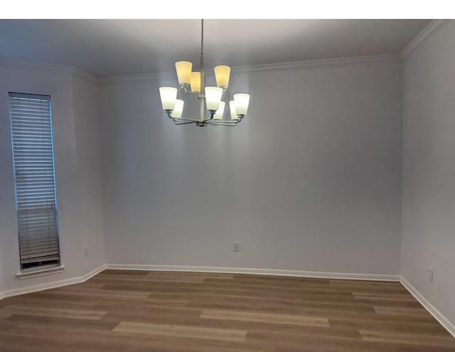 spare room with an inviting chandelier, baseboards, crown molding, and wood finished floors