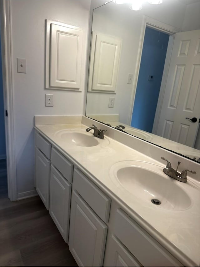 bathroom featuring double vanity, a sink, and wood finished floors