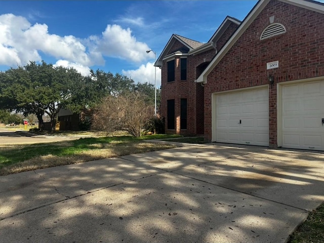 view of property exterior featuring concrete driveway and brick siding