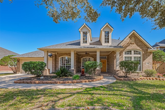 view of front of home with driveway, a shingled roof, an attached garage, a front yard, and brick siding