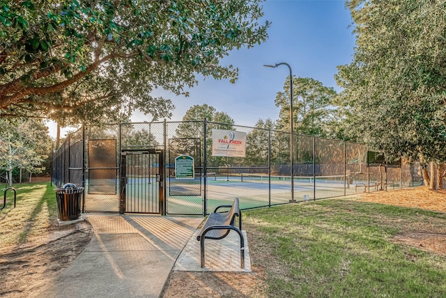 view of tennis court featuring a yard, a gate, and fence