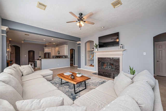 living room featuring light tile patterned floors, visible vents, and arched walkways